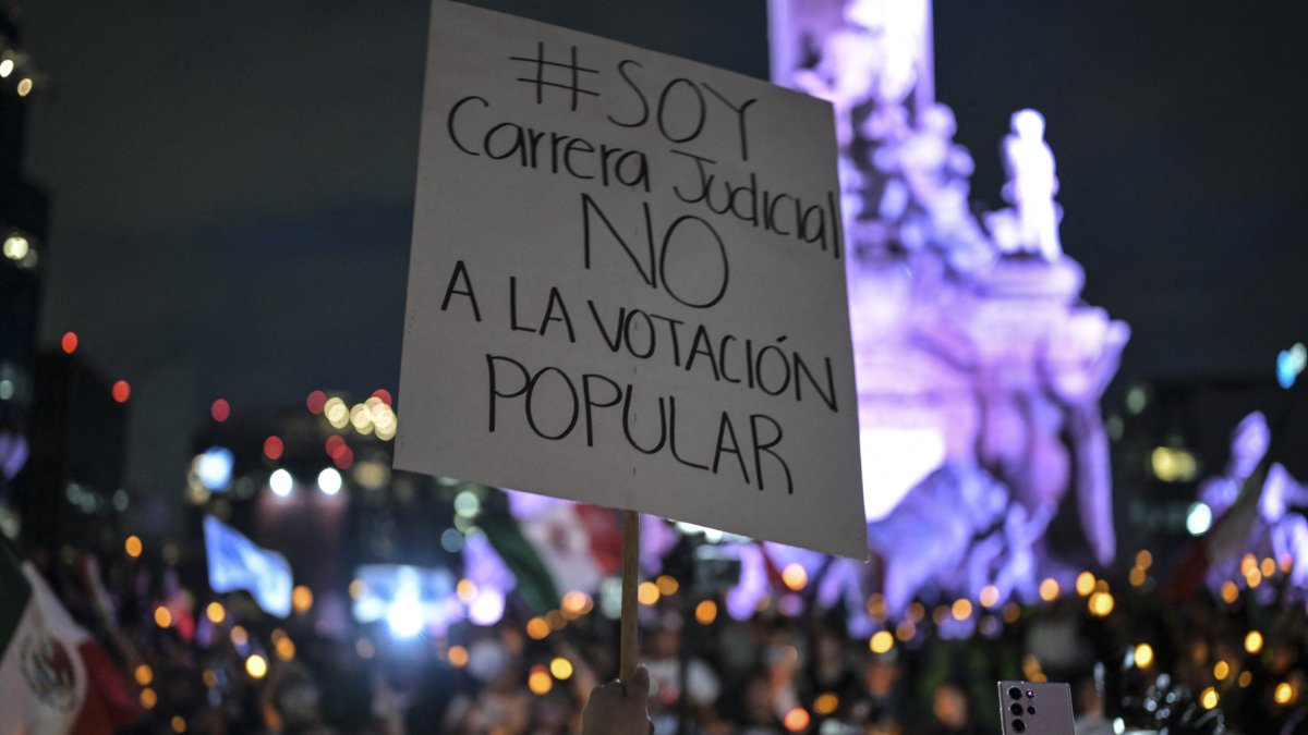 Un manifestante sostiene un cartel contra la reforma judicial de AMLO