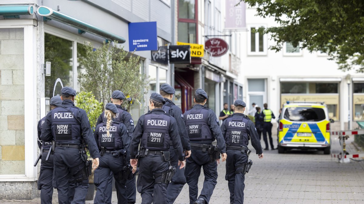 25 August 2024, North Rhine-Westphalia, Solingen: Police officers walk past the scene at midday. Three people were killed and several injured in an attack at the 650th anniversary celebrations of the city of Solingen on 23.08.2024. Photo: Thomas Banneyer/dpa