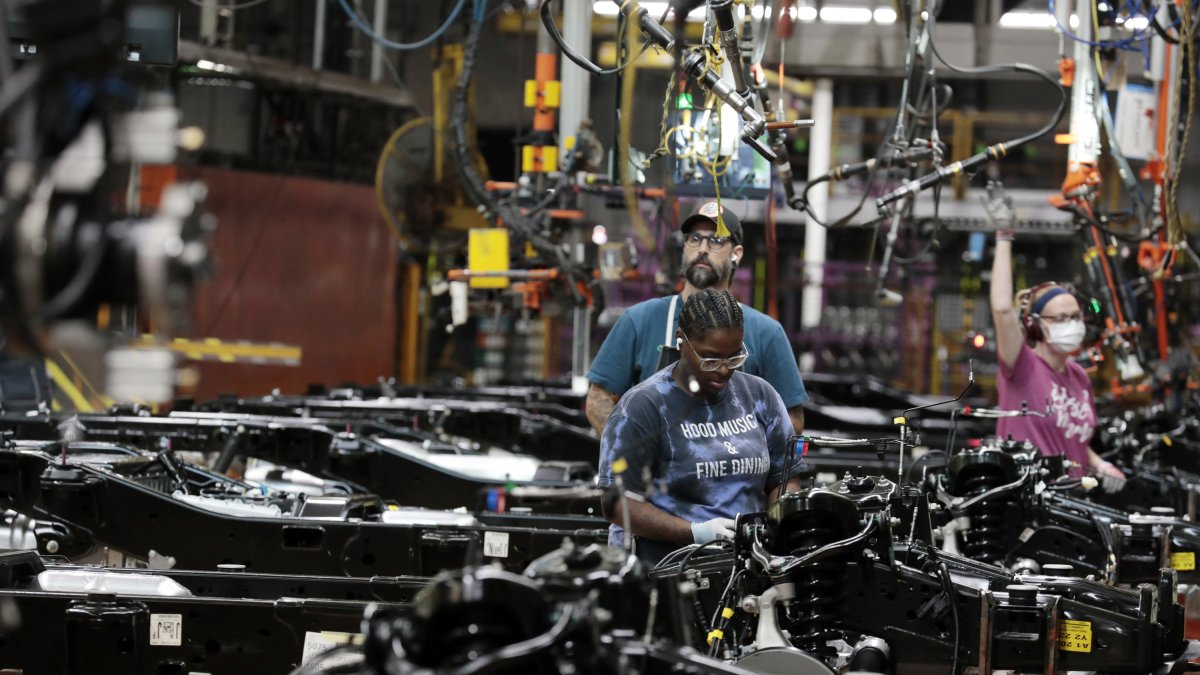 El 20 de septiembre de 2022, en la planta de camiones de Dearborn, Michigan, los trabajadores de Ford Motor Co. colocan los motores en el bastidor de los camiones F-150 de combustible en producción.