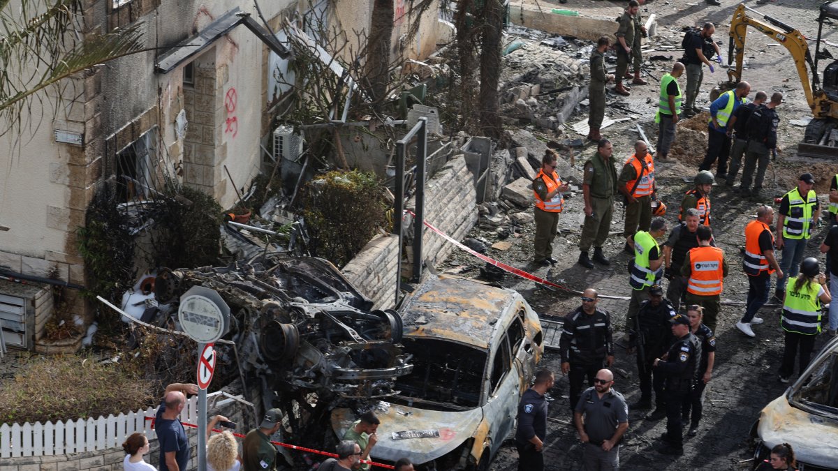 Varias personas observan el estado de varios vehículos en  Kiryat Bialik (Haifa) tras el ataque de Hizbulá.