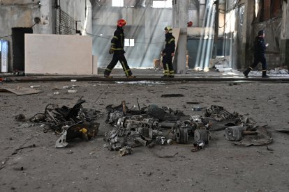 Ukrainian soldiers walk in front of downed drone wreckage.