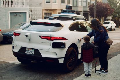 Una mujer y un niño suben a un robotaxi.