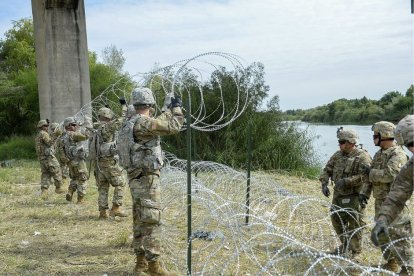 Militares de la Guardia Nacional en la frontera con México levantan una alambrada.