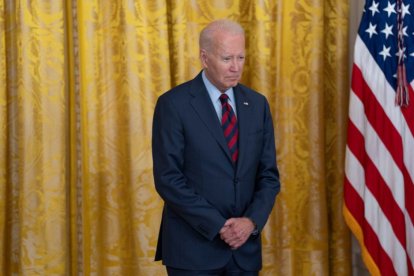 El presidente Biden parado frente a una cortina dorada.