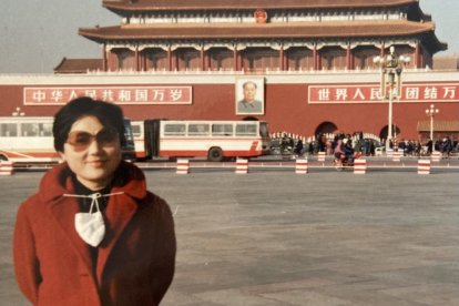 Xi Van Fleet en China frente a un edificio decorado con motivos comunistas, incluyendo una fotografía de Mao Zedong.