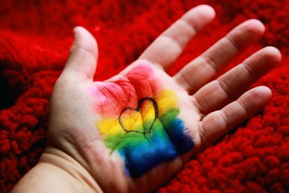 Mano de un niño pintada con los colores de la bandera LGBT y un corazón.