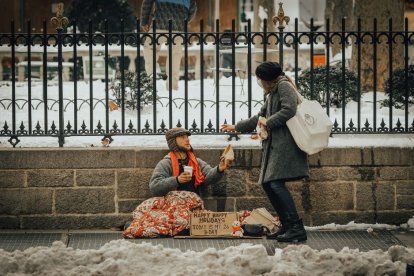 Una mujer entrega una ayuda a un homeless