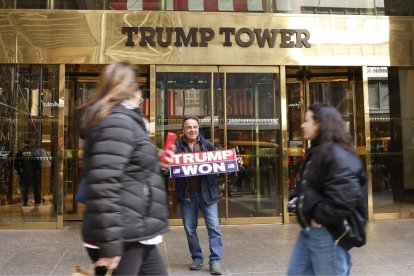 Un simpatizante de Donald Trump con un cartel de apoyo al expresidente en las puertas de la Torre Trump de Nueva York.