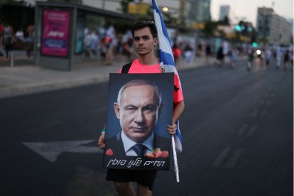 Un manifestante israelí posa con un retrato de Benjamin Netanyahu.