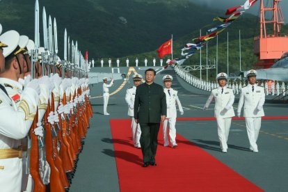 Xi Jinping camina al lado de miembros de las fuerzas armadas antes de abordar el portaviones Shandong.