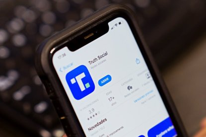 Una mano sosteniendo un móvil en el que sale la aplicación Truth Social para ser descargada en el celular.