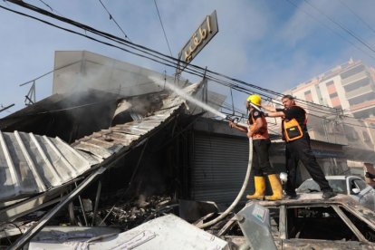 Fotografía de bomberos apagando un incendio provocado tras un ataque aéreo en Gaza.