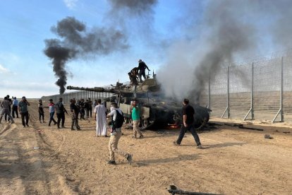 Imagen de archivo de terroristas de Hamás quemando un vehículo militar israelí en la frontera de Israel con Gaza.