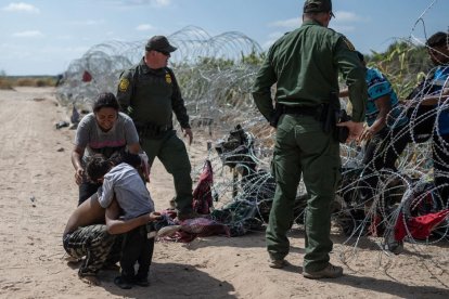 Una familia intentando ingresar a Estados Unidos rompe el alambrado de púas.