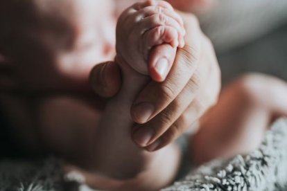 Un padre toma la mano de su recién nacido.