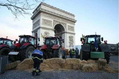 Policías observan tractores aparcados junto al Arco del Triunfo en la avenida de los Campos Elíseos durante una protesta del sindicato de agricultores franceses en París el 1 de marzo de 2024.