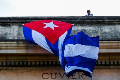 Un hombre ata una bandera cubana en el techo de la Universidad de La Habana