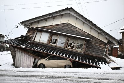 Un coche dañado yace bajo un edificio derrumbado en la ciudad de Shika, en el distrito de Hakui, prefectura de Ishikawa, el 8 de enero de 2024.