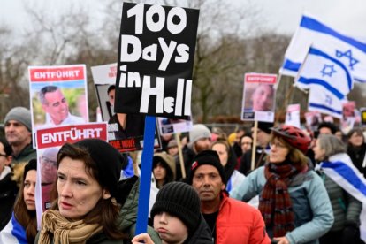 Demonstrators carry Israeli flags and placards with the portraits of Israeli hostages during a march to mark the 100th day of the Israeli hostages' captivity during the ongoing Israeli-Palestinian conflict, on January 14, 2024 in Berlin.