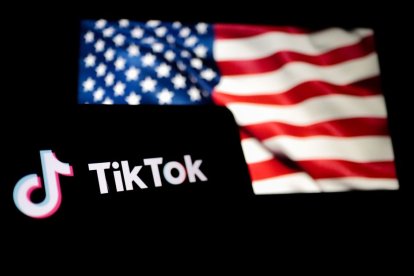 Un smartphone con el logo de TikTok delante de una bandera de los Estados Unidos.