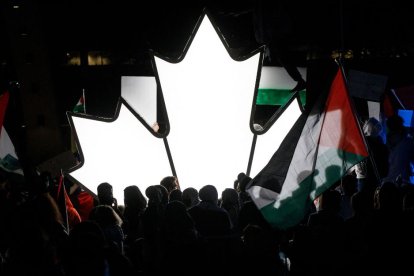 Un grupo de personas junto a una hoja de arce canadiense iluminada mientras miles de personas se reúnen en Toronto (Ontario, Canadá) para mostrar su apoyo a Palestina.