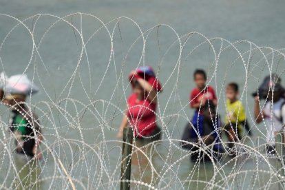 Un grupo de migrantes busca una abertura en la barrera de alambre concertina | Cordon Press