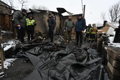 Algunos policías se paran frente a cuerpos cubiertos con bolsas de plástico en el lugar de un ataque con drones en Kharkiv