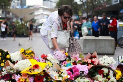 Una mujer deposita flores frente al centro comercial Westfield en Bondi Junction, en Sídney, Australia, el 14 de abril de 2024.