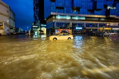 Un taxi circula por una calle inundada tras las fuertes lluvias caídas en Dubai la madrugada del 17 de abril de 2024. Dubai, el centro financiero de Oriente Medio, ha quedado paralizado por las lluvias torrenciales que provocaron inundaciones en los EAU y Bahréin y dejaron 18 muertos en Omán los días 14 y 15 de abril.