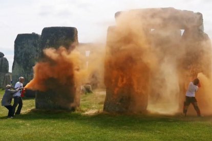 Una imagen tomada de un video publicado por el grupo de campaña climática Just Stop Oil muestra a activistas rociando una sustancia naranja en Stonehenge en Wiltshire, suroeste de Inglaterra