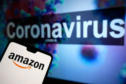 Logotipo de Amazon en un teléfono móvil con un modelo ilustrativo del coronavirus en un monitor de fondo. El crédito de la foto debe decir: James Warwick/EMPICS Entertainment