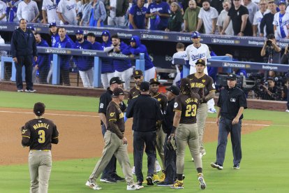 Los jugadores de los Padres de San Diego reciben instrucciones mientras que el Juego 2 de la NLDS del domingo 6 de octubre de 2024 se detiene debido a que los aficionados lanzan basura y pelotas de béisbol al campo en la 7ª entrada del partido entre los Dodgers de Los Ángeles y los Padres de San Diego en el Dodger Stadium de Los Ángeles, California. Jurickson Profar y Fernando Tatis hablan con los árbitros mientras les lanzan pelotas y basura.