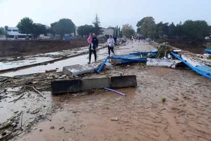 Miembros de una familia caminan por una calle cubierta de barro tras las inundaciones