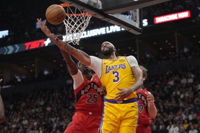 nba: El alero de Los Angeles Lakers Anthony Davis (3) recibe una falta del alero de Toronto Raptors Chris Boucher (25) mientras va a encestar durante la primera mitad en el Scotiabank Arena.