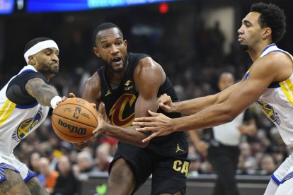 El alero de los Cleveland Cavaliers Evan Mobley (4) regatea entre el escolta de los Golden State Warriors Gary Payton II (0) y el alero Trayce Jackson-Davis (32) en el primer cuarto en el Rocket Mortgage FieldHouse.