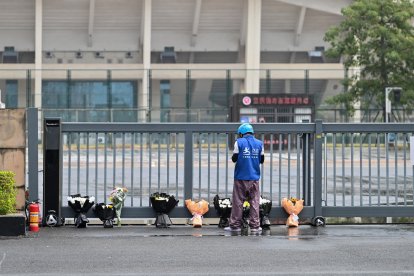 Un repartidor deposita pedidos online de ramos de flores en un monumento improvisado frente al Centro Deportivo de Zhuhai