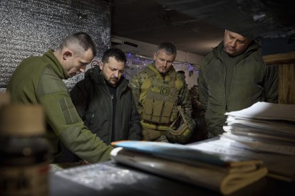 El presidente ucraniano Volodimir Zelenski es informado por un comandante durante su visita a un cuartel.