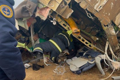 Unos bomberos revisan el lugar de colisión del avión de Azerbaijan Airlines, en el que quedan restos de la aeronave.