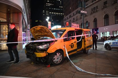 Un taxi accidentado, sni las partes delanteras del chasis, descansa en una zona acornada de una acera de Nueva York.