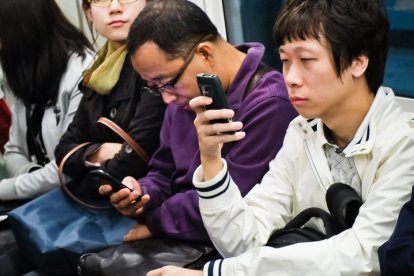 Ciudadanos chinos miran su teléfono