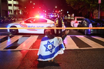 A man carrying the Israeli flag approaches the scene of the crime.