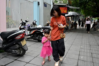 A mother holding hands with her young daughter in Hanoi.