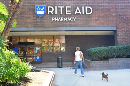 A woman enters a Rite Aid pharmacy with her pet.