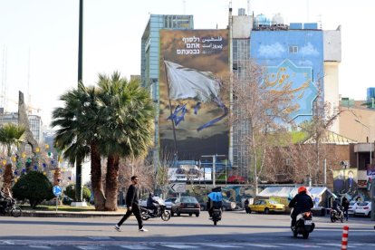 Iraníes pasan junto a un cartel antiisraelí en la Plaza Palestina de Teherán