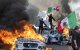 Manifestantes ondean banderas desde lo alto de un coche destrozado, junto a vehículos Waymo en llamas, mientras los manifestantes se enfrentan a las fuerzas del orden en las calles que rodean el edificio federal durante una protesta tras las operaciones federales de inmigración en Los Ángeles, California, el 8 de junio de 2025. Manifestantes incendiaron coches y se enfrentaron a las fuerzas de seguridad en Los Ángeles el 8 de junio, mientras la policía mantenía a los manifestantes alejados de las tropas de la Guardia Nacional que el presidente Donald Trump envió a las calles de la segunda ciudad más grande de EE.UU.(Foto de RINGO CHIU / AFP)