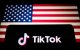 El logotipo de TikTok se muestra en un smartphone junto a la bandera de Estados Unidos. TikTok es una aplicación lanzada en 2016 por ByteDance, una empresa tecnológica china.