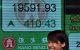 Una mujer sonríe al pasar junto a un tablón de anuncios que muestra el índice Hang Seng en Hong Kong el 16 de septiembre de 2011.
