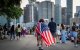Una persona se envuelve con una bandera de Estados Unidos como una capa mientras la multitud se reúne para la celebración de los fuegos artificiales del 4 de Julio de Macy’s a lo largo del río Este