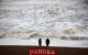 People look at the waves while standing behind a warning sign reading "Danger" (Files)