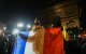 Un agricultor sostiene una bandera francesa frente al Arco del Triunfo.